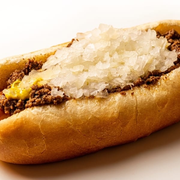 Hot dog with chili, mustard, and chopped onions in a bun on a white background.
